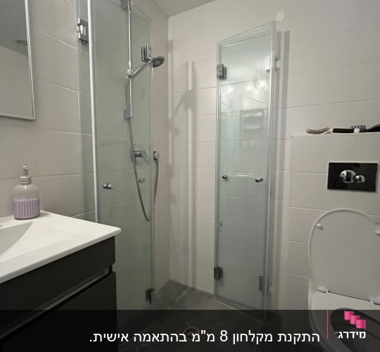 מקלחת עם דלתות זכוכית, כיור ואסלה